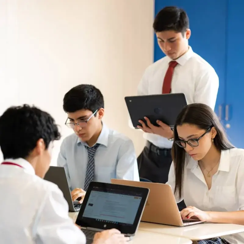 Estudiantes trabajando colaborativamente con dispositivos tecnológicos durante una clase en el instituto